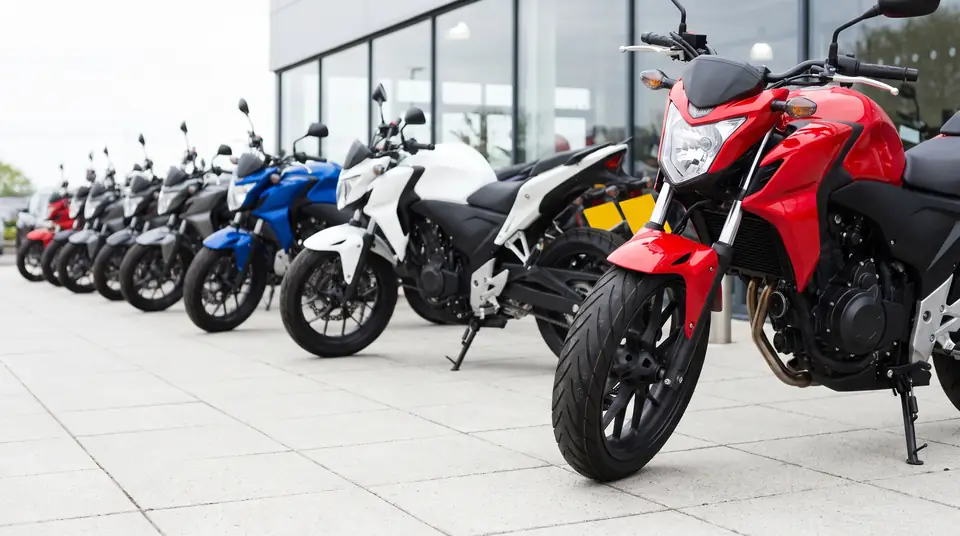 A row of new motorcycles lined up outside a glass-fronted showroom